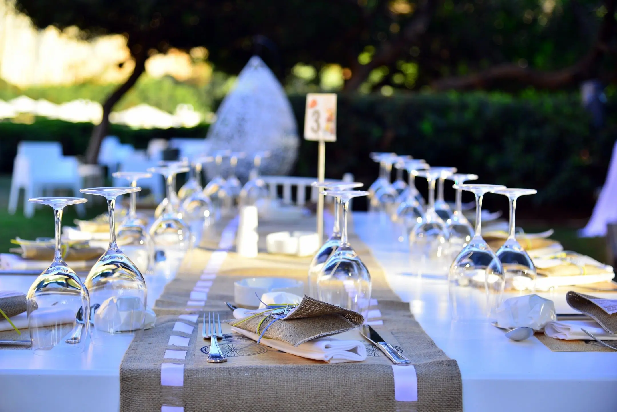 Elegant outdoor dining setup with wine glasses and a centerpiece.